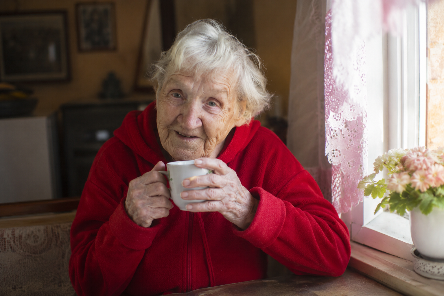 Elderly woman peaceful at a sunny window with morning coffee